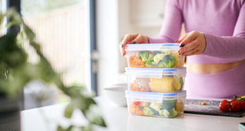 Woman stacking up containers of food for meal planning