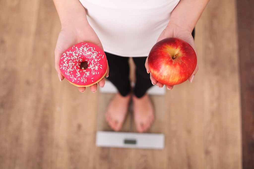 woman standing on scales debating weight loss roadblocks for women